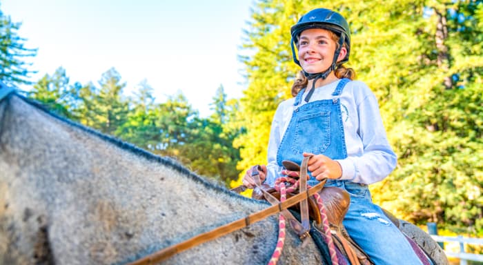 A girl on a horse in overalls