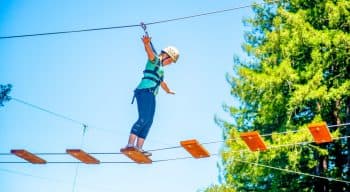 Girl walks across planks of ropes course