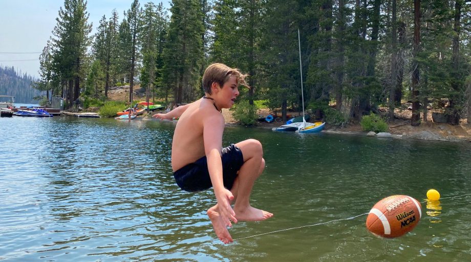 boy jumping with football at Huntington Lake